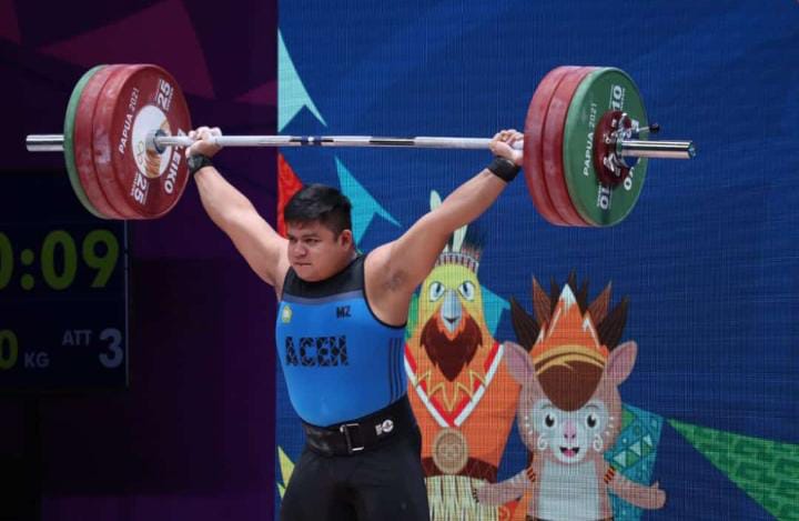 Lifter Aceh Zul Ilmi saat tampil di PON Papua 2021 cabang olahraga angkat besi di Auditorium Universitas Cenderawasih, Jum'at (8/10/2021). Foto: KONI/Satria