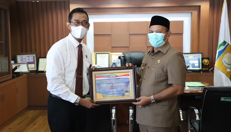 Kepala Kantor Wilayah Direktorat Jenderal Perbendaharaan Provinsi Aceh, Syafriadi menyerahkan penghargaan dari Menteri Keuangan Sri Mulyani Indrawati kepada Bupati Aceh Besar Ir H Mawardi Ali di ruang kerja Bupati Aceh Besar, Senin (1/11/2021). Foto: Ist