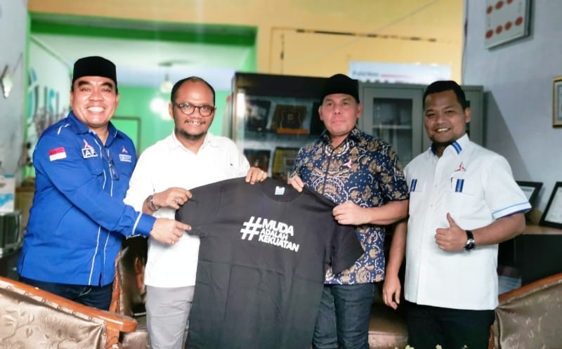 Ketua DPD Demokrat Aceh, Muslim, SHI, MM saat menyerahkan bingkisan titipan Ketua Umum DPP Partai Demokrat, Agus Harimurti Yudhoyono (AHY) berupa baju kaos bertulisan #MUDAADALAHKEKUATAN kepada Owner media Dialeksis dan Nukilan, Aryos Nivada. (Foto: Nukilan/JI)
