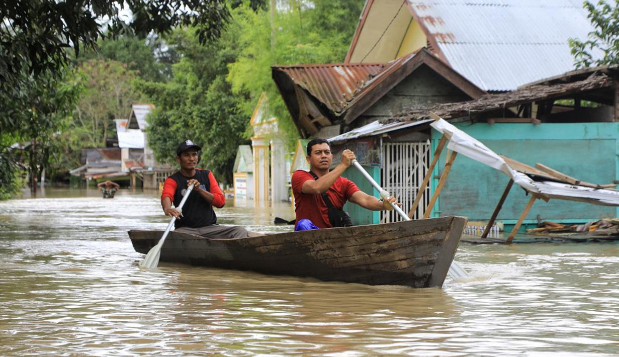 Warga mendayung perahu kayu saat banjir di Lhoksukon, Aceh Utara, 3 Januari 2022. Berdasarkan data Badan Penanggulangan Bencana Daerah (BPBD) Aceh Utara, banjir mengakibatkan 2.278 jiwa terdampak dan satu orang anak meninggal dunia. (Foto: Azwa Ipank/AFP)