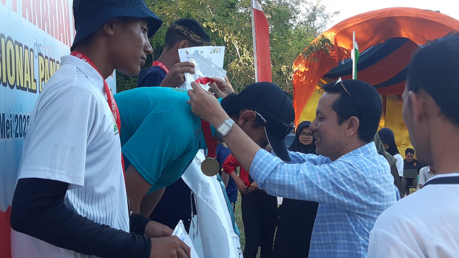 Sekjen PB Perpani, Prof Dr Nyak Amir, M.Pd mengalungkan medali kepada pemenang divisi nasional Indonesia Open/Sirnas stage 1 yang digelar di lapangan Tugu, Darussalam Banda Aceh, 22  - 28 Mai 2022. Foto : Humas Perpani Aceh.