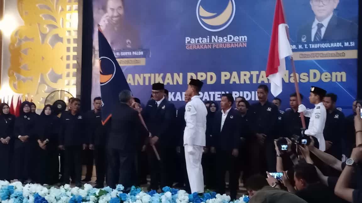 Teuku Taufiqulhadi menyerahkan Pataka Partai Nasdem kepada Fadhlullah TM Daud sewaktu melantik Pengurus DPD Partai Nasdem Kabupaten Pidie. (Foto: Ist)