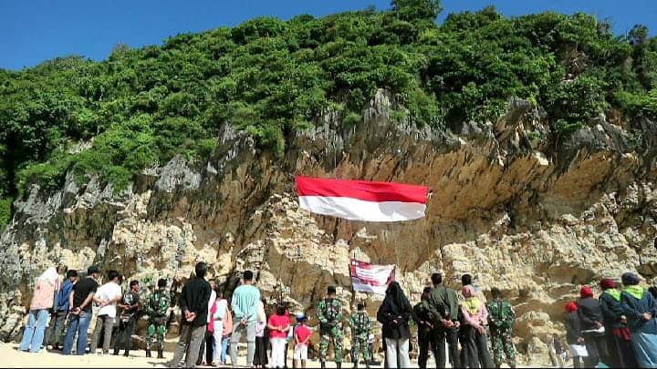 Pemanjat tebing profesional dari Gainpala sedang membentangkan bendera raksasa di Tebing Pantai Lampuuk, Lhoknga, Aceh Besar, Rabu (17/8/2022). Foto: Nukilan/Reji.