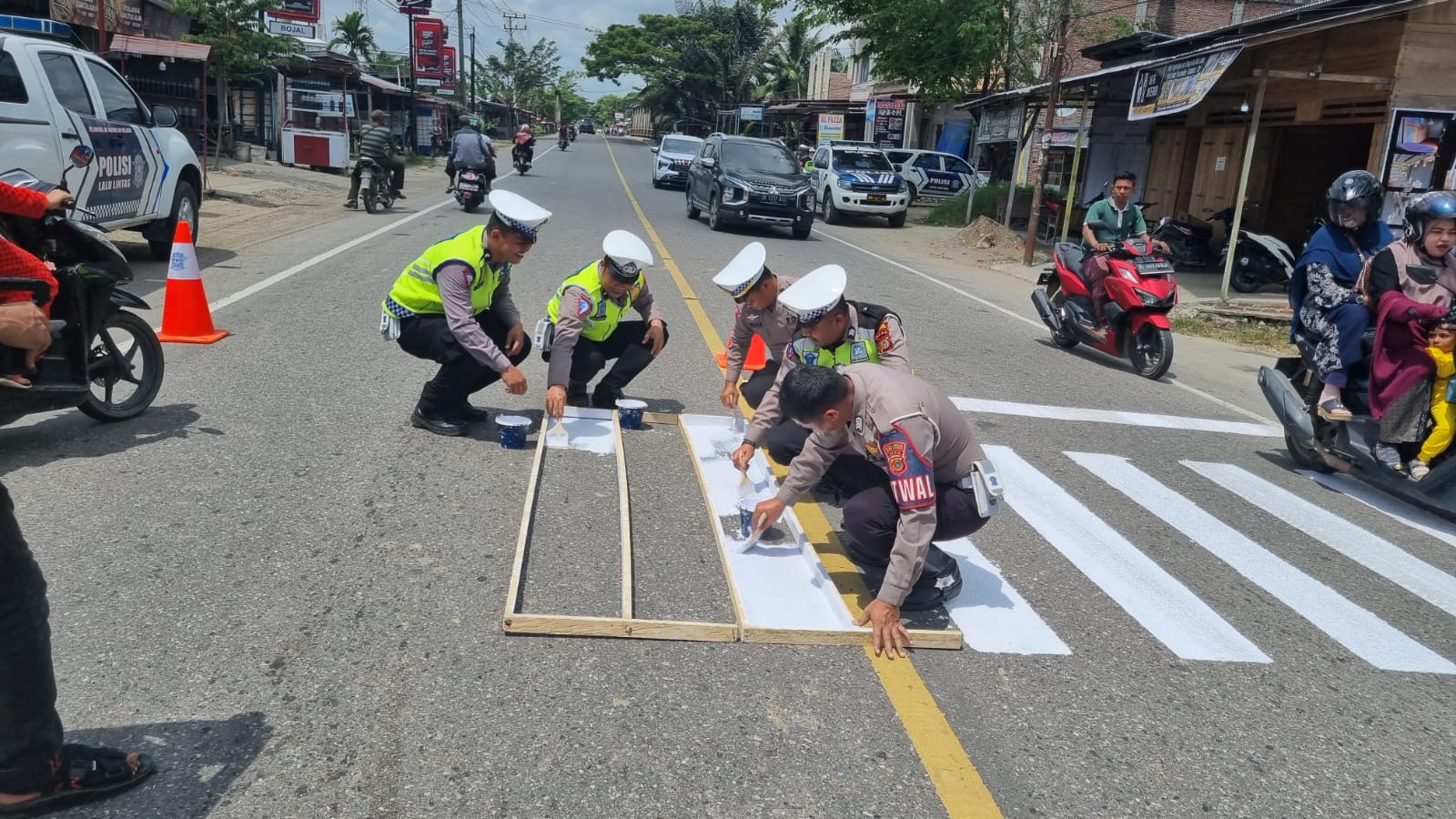 Satlantas Polres Aceh Utara mengecat marka jalan atau zebra cross di jalan nasional Banda Aceh-Medan, Kecamatan Baktiya Barat, Kabupaten Aceh Utara, Minggu 12 Maret 2023. (Foto: Ist)