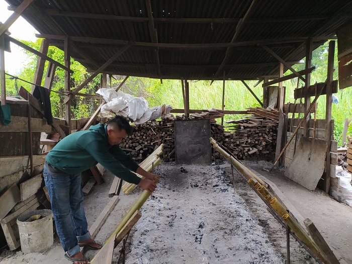 Salah seorang pedagang lemang di wilayah Lamdingin, Kecamatan Kuta Alam, Kota Banda Aceh yang sedang melakukan proses pembakaran lemang, Kamis (20/3/2023). (Foto: Nukilan/Azril)