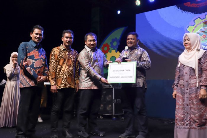 Pj Bupati Aceh Besar, Muhammad Iswanto, SSTP, MM didampingi Kepala DPMG Aceh Dr Ir Zulkifli MSi menyerahkan piala kepada pemenang Juara pertama stand terbaik Gelar TTG XXlV Aceh dan diterima Sekdakab Aceh Besar Drs Sulaimi MSi, di Komplek Jantho Sport. (Foto: Ist)