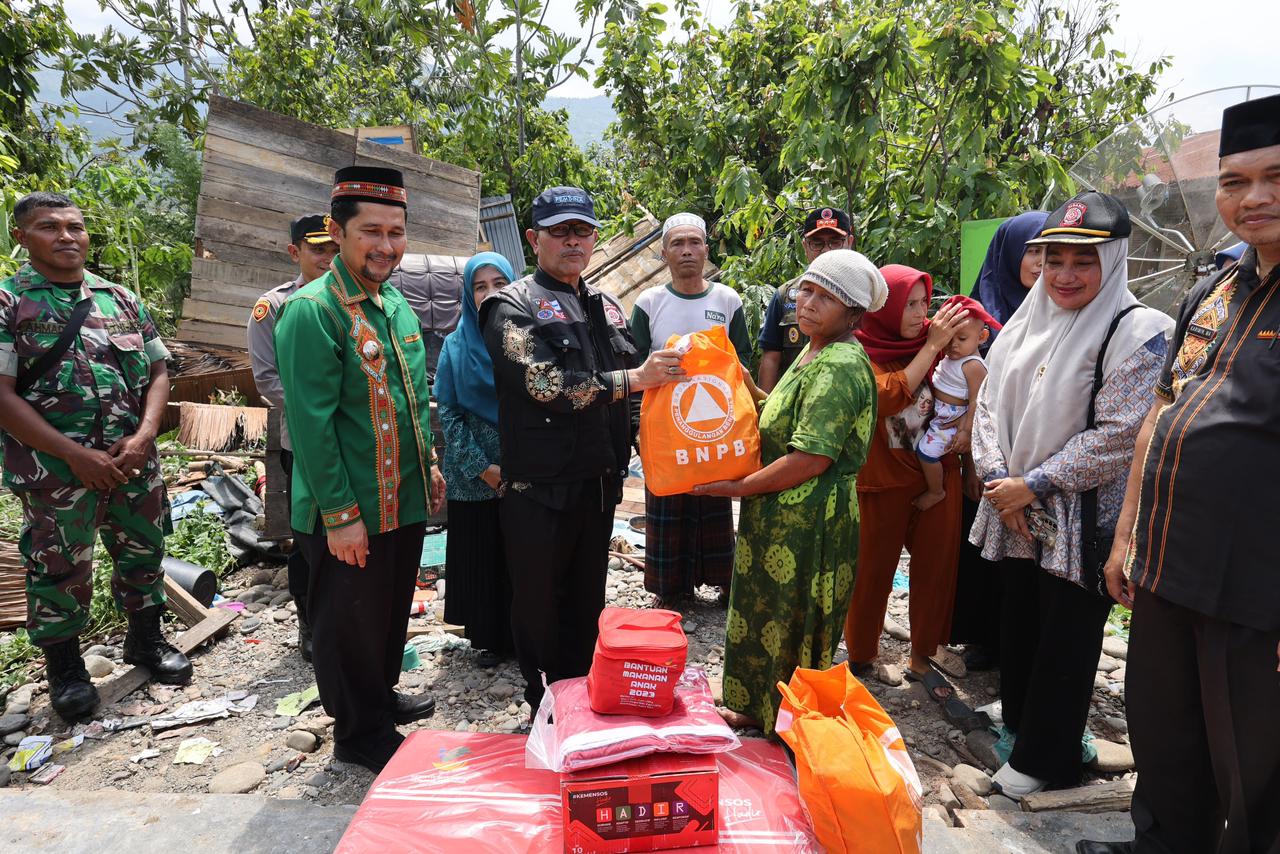 Kadinsos Aceh, Dr. Muslem Yacob di dampingi Pj Bupati Aceh Tenggara, Drs. Syakir, M.Si menyerahkan bantuan  masa panik kepada warga. (Foto: Dok Pribadi)