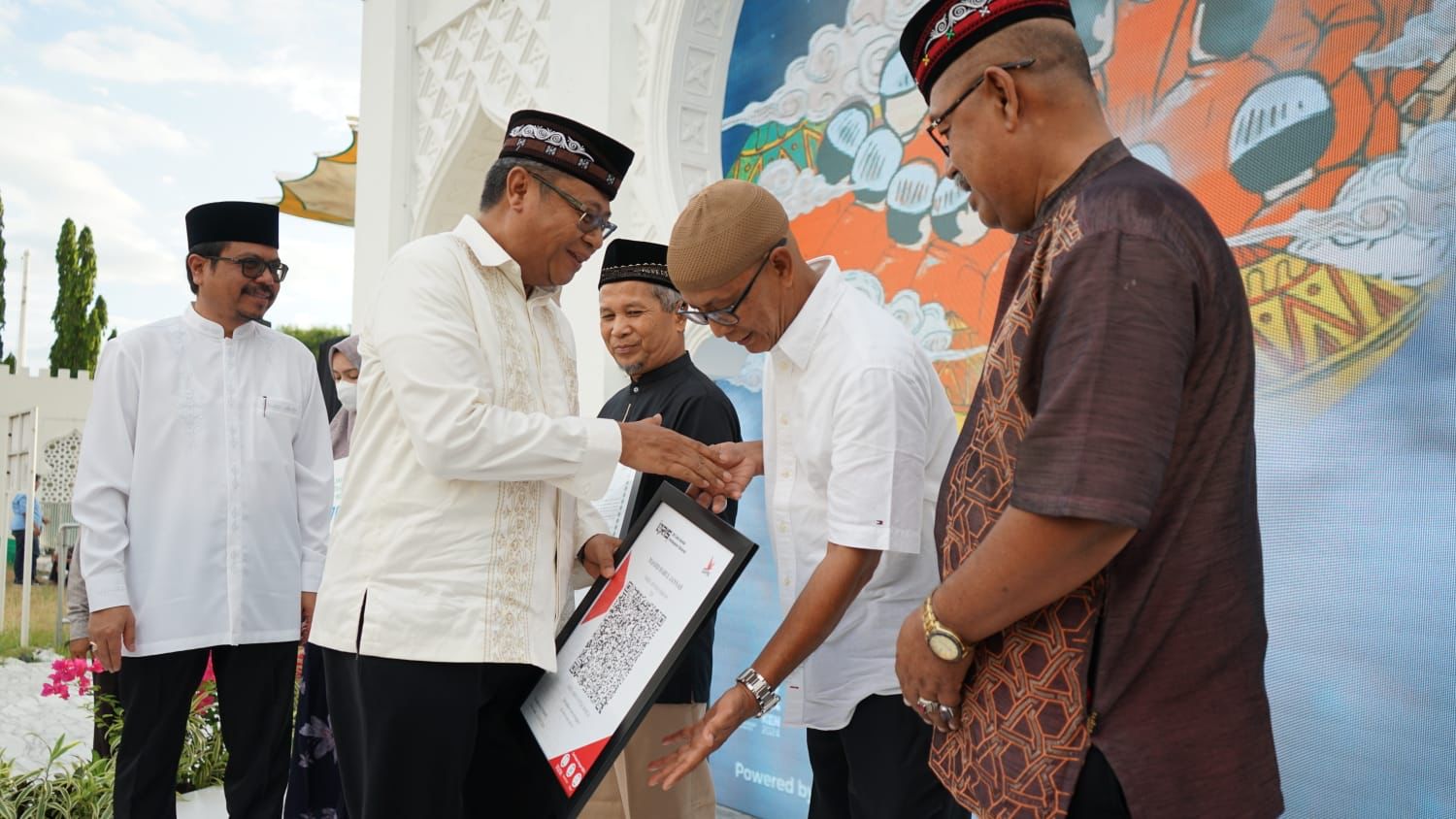Kepala Perwakilan BI Provinsi Aceh, Rony Widijarto saat menyerahkan Qris kepada pengurus Masjid kepada Pengurus Masjid Babul Jannah. (Foto: For Nukilan)