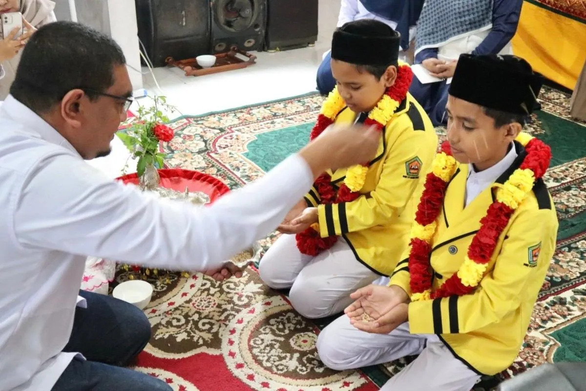 Kepala Kantor Kemenag Aceh Besar Saifuddin saat melakukan prosesi adat peusijuk kepada dua pelajar MIN yang lolos ke olimpiade matematika tingkat Asia Tenggara. (Foto: ANTARA)