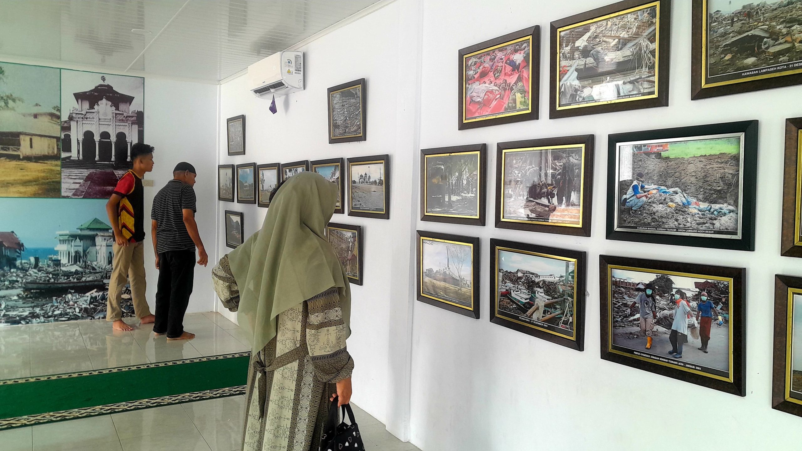 Pengunjung sedang melihat foto-foto di Ruang Galeri aiturrahim Ulee Lheue. (Foto: Nukilan)