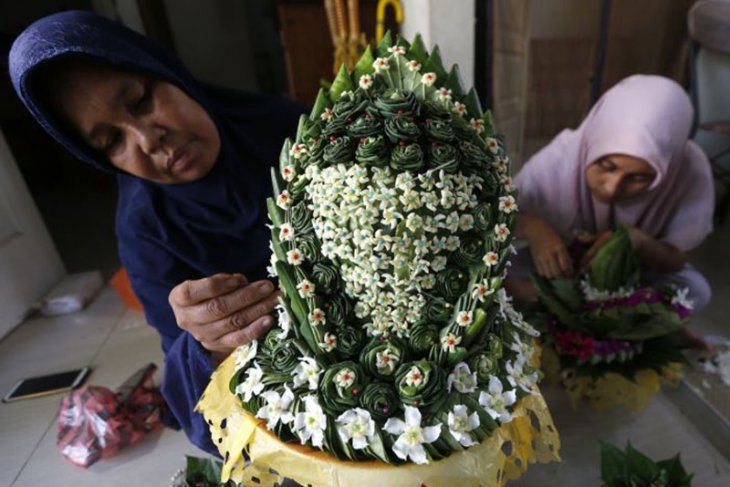 Perajin merangkai daun sirih menjadi bentuk topi tradisional kupiah meuketop. (Foto: ANTARA)