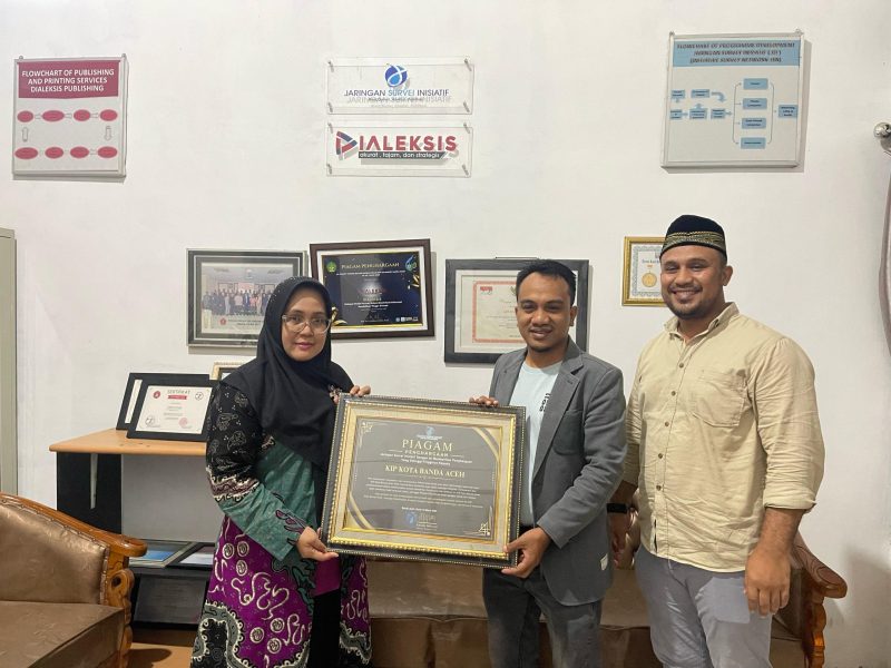 Direktur Eksekutif JSI, Ratnalia Indriasari, menyerahkan pernghargaan kepada Ketua KIP Kota Banda Aceh, Yusri Razali, didampingi Komisioner KIP Kota Banda Aceh, Muhammad Zar, di Kantor JSI, Banda Aceh, Selasa 11 Maret 2025. (Foto: Nukilan)