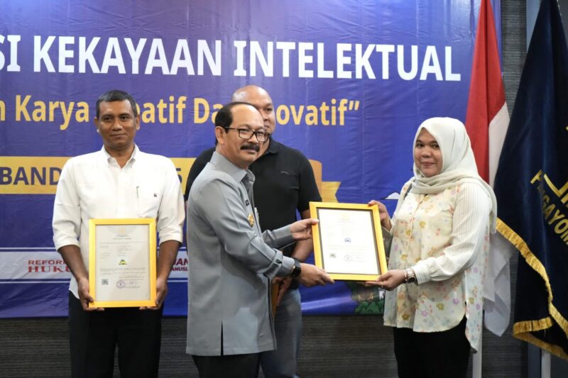 Kakanwil Kemenkum Aceh Meurah Budiman menyerahkan sertifikat merek kepada pelaku usaha di Aceh pada Selasa (6/5) di Hotel Kyriad Muraya, Banda Aceh. (Foto: InfoAceh.Net)