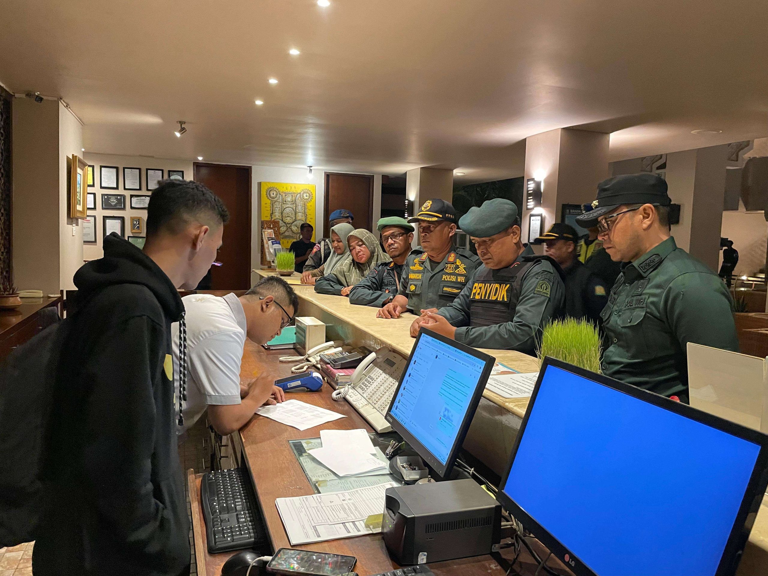 Kasatpol PP dan WH Aceh Besar Muhajir SSTP MPA, bersama Penyidik Satpol PP dan WH Aceh Marzuki, serta para petugas, melakukan pengecekan daftar tamu salah satu hotel di Aceh Besar, Sabtu (24/5/2025) malam. (FOTO: MC ACEH BESAR)