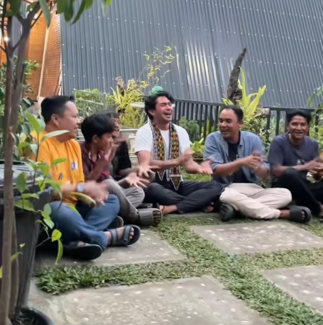 Reza Rahardian tampak duduk bersama delapan warga lokal dan mengikuti irama dengan menepuk-nepuk tangan, gerakan khas dari pertunjukan didong. (Foto: Tangkapan Layar)