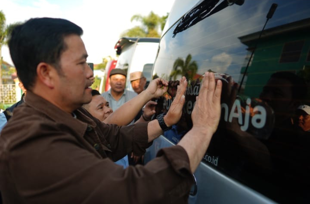 Bupati Haili Yoga memasang stiker promosi wisata 'Di Takengon Aja' di salah satu mobil HiAce. (Foto: Istimewa)