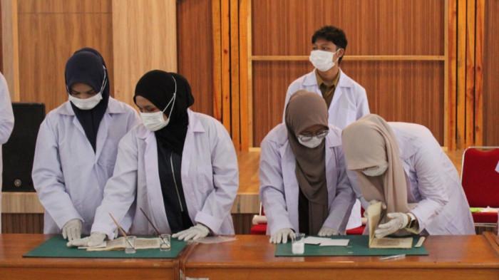 Sejumlah mahasiswa Program Studi Ilmu Perpustakaan Fakultas Adab dan Humaniora (FAH) UIN Ar-Raniry saat mengikuti praktik restorasi naskah kuno di Aula Museum Aceh, Selasa (28/10/2025). (Foto: For Nukilan)