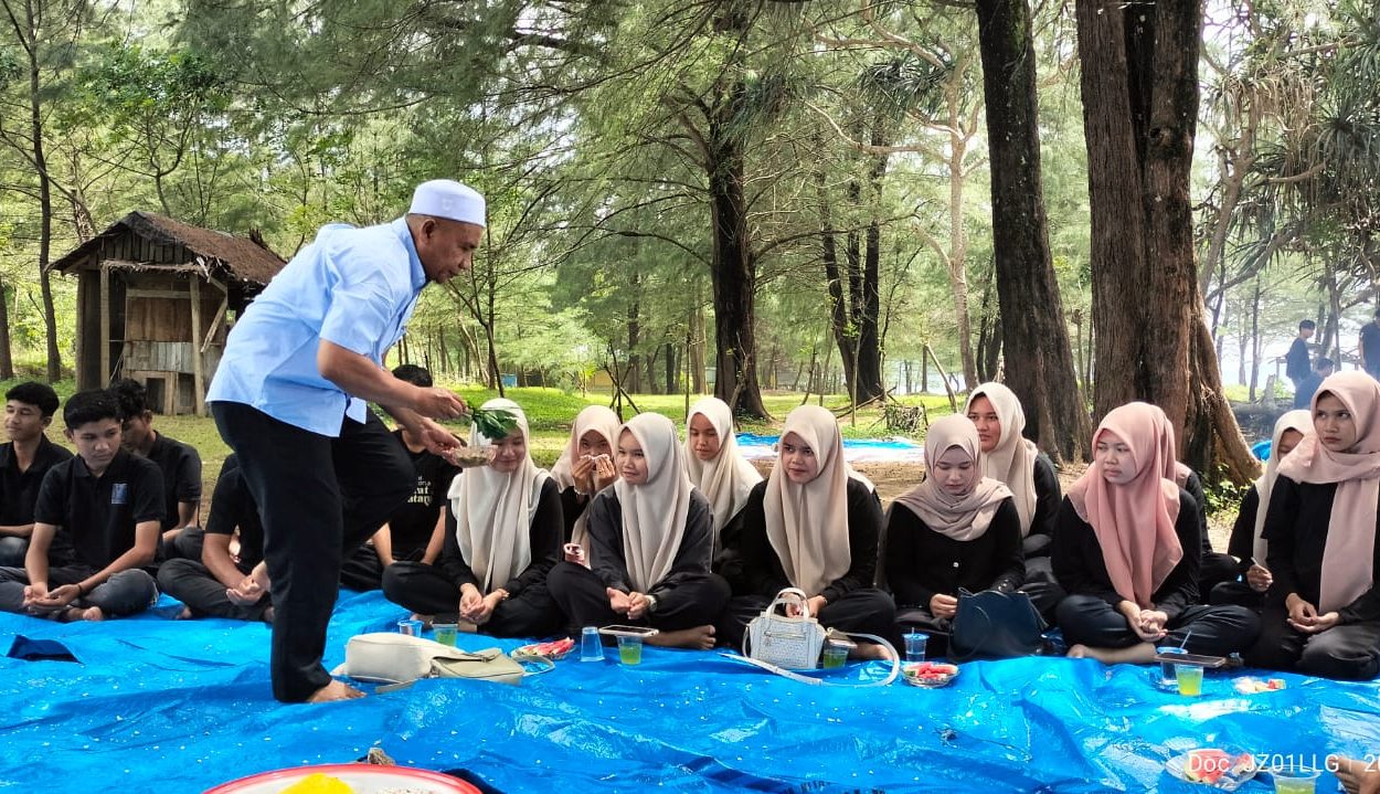 Ketua Pembina Komunitas Rajolelo, Kusnadi, S.Ag., M.A., melakukan prosesi peusijuek kepada mahasiswa baru tahun ajaran 2025–2026 di Pantai Riting Stable, Leupung, Aceh Besar, Minggu (26/10/2025). (Foto: For Nukilan)