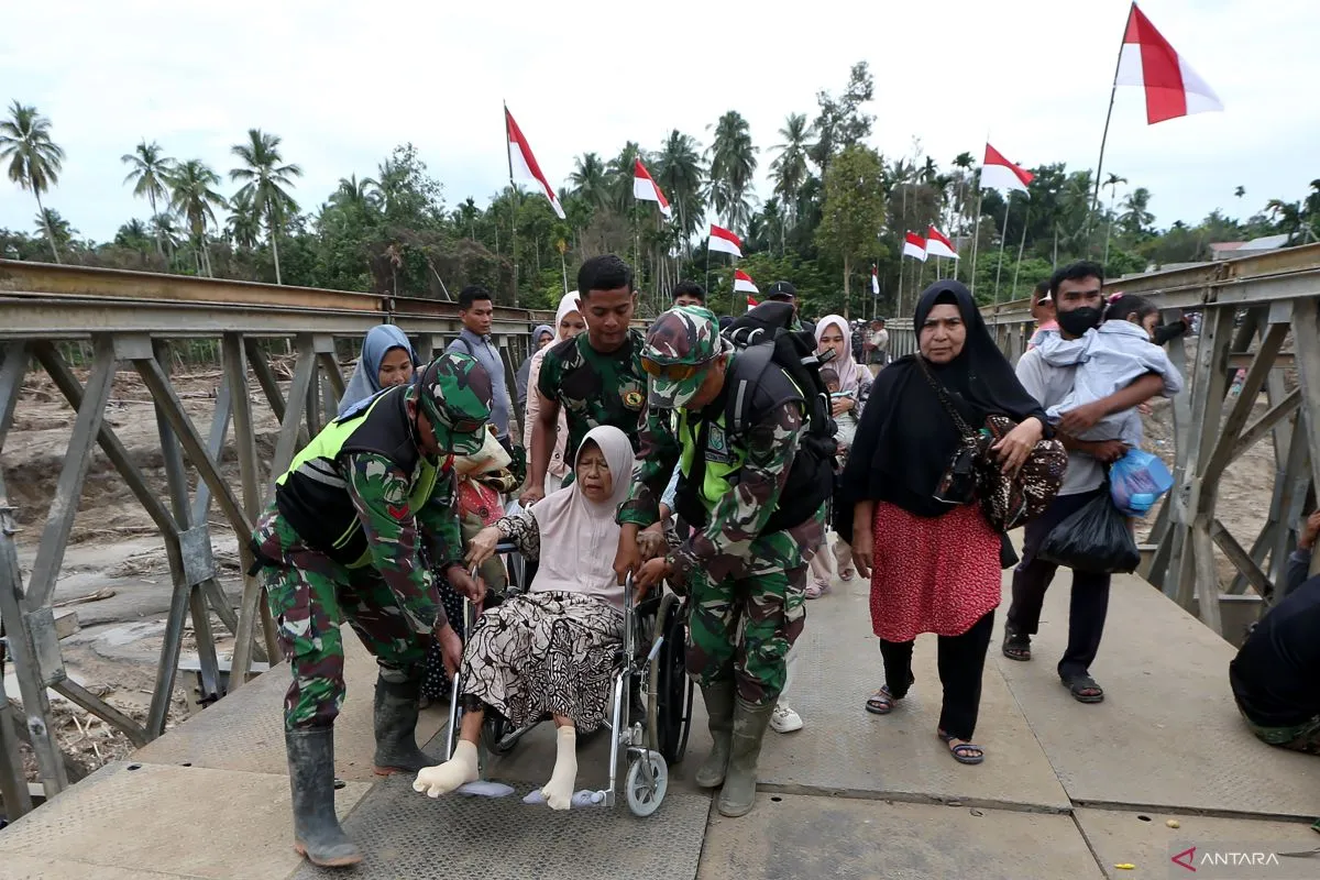 Prajurit TNI membantu warga saat melewati Jembatan Bailey Awe Geutah yang baru selesai dibangun setelah sebelumnya putus akibat bencana banjir bandang di Bireuen, Aceh, Kamis (18/12/2025). (Foto: ANTARA FOTO)
