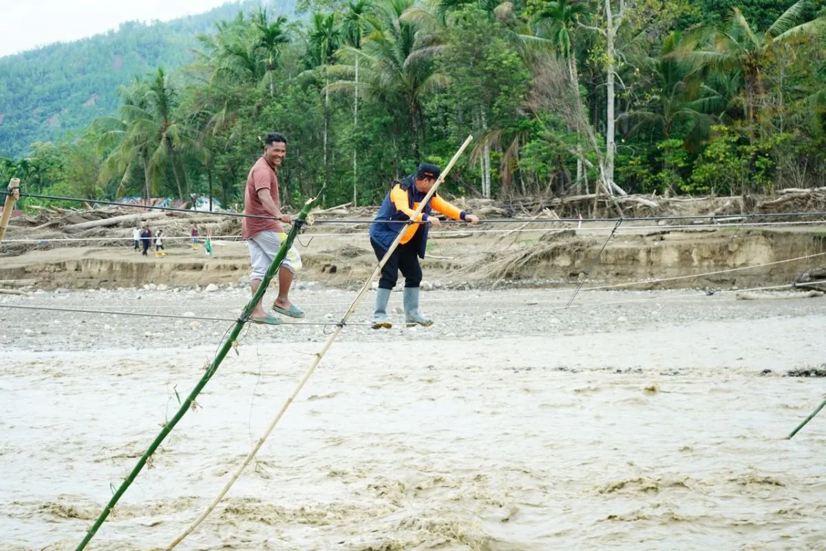Bupati Aceh Tengah Haili Yoga melintas di jembatan tali, di mana jembatan sebelumnya hilang diterjang banjir. (Foto: Humas Aceh Tengah)