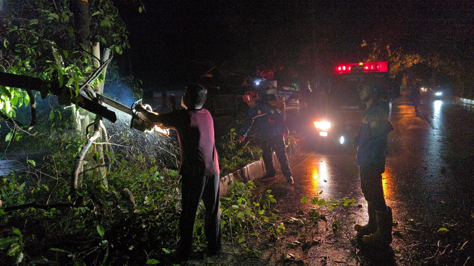 Pembersihan pohon tumbang yang menutupi badan jalan akibat hujan lebat disertai angin kencang di salah satu wilayah Aceh Besar, Selasa (19/5/2026) malam. (Foto: Dok BPBD Aceh Besar)